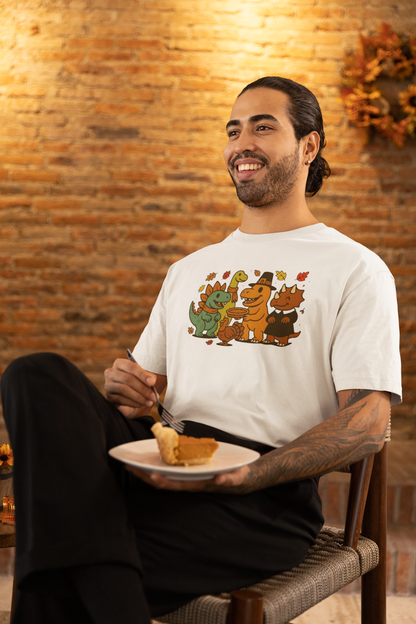 Thanksgiving Dinosaur T-Shirt – Funny Dino Thanksgiving Tee with adorable dinosaurs in autumn colors, worn by a man enjoying a slice of pumpkin pie at a warm fall-themed dinner table.