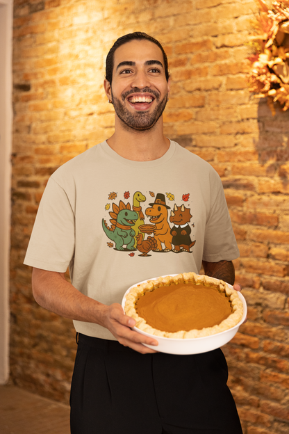 Thanksgiving Dinosaur T-Shirt – Funny Dino Thanksgiving Tee featuring cheerful cartoon dinosaurs celebrating the holiday, shown on a smiling man holding a fresh pumpkin pie in a cozy brick-walled kitchen.