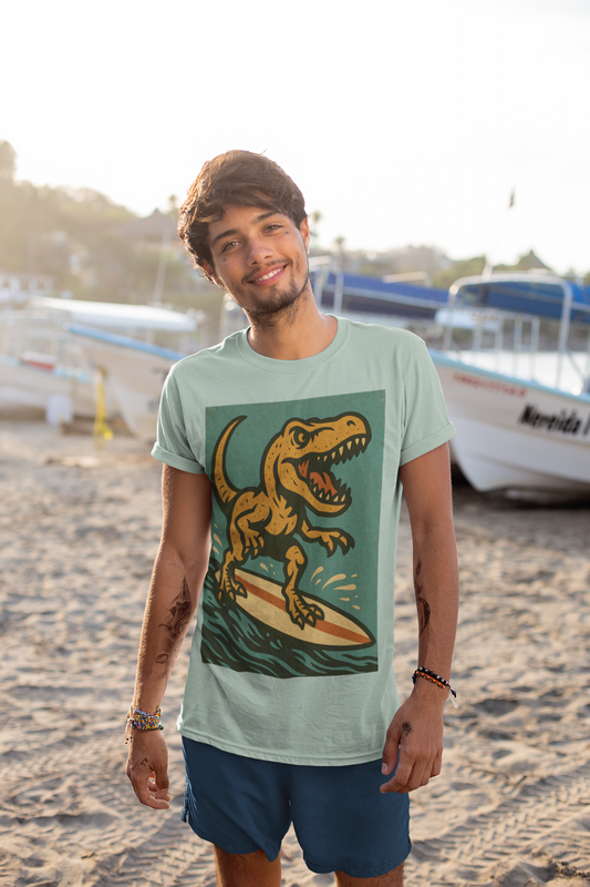 A man wearing the Surfing T-Rex T-Shirt – Funny Dinosaur Graphic Tee for Summer Vibes from  WhimSpin stands on a beach with boats in the background. The image on the shirt features an orange T-rex roaring while riding a yellow surfboard on top of waves. 