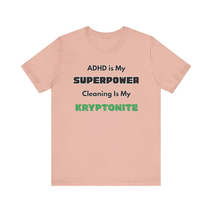 ADHD Cleaning Kryptonite T-Shirt – Funny Shirt for Neurodivergent Humor in peach with bold text emphasizing ADHD and kryptonite