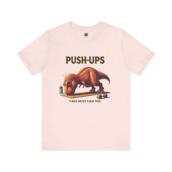 T-Rex Push-Up T-Shirt – Funny Dinosaur Workout Graphic Tee in soft pink with a cute yet fierce t rex hates push ups joke for quirky gym-goers.