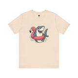 Shark Flamingo Floatie T-Shirt – Funny Beach & Pool Day Tee in soft cream with lighthearted cartoon of shark in floatie