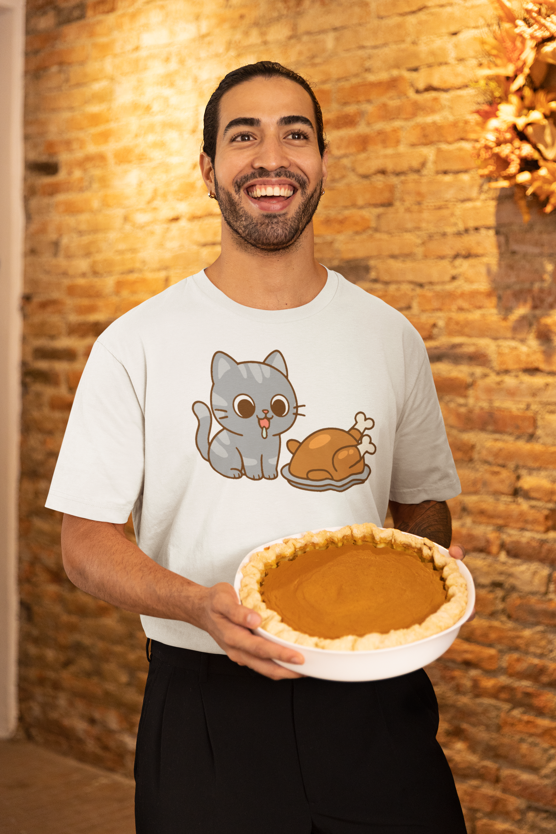 Thanksgiving Cat T-Shirt – Cute Hungry Cat and Turkey Tee shown on man in white shirt smiling with pumpkin pie in rustic fall setting