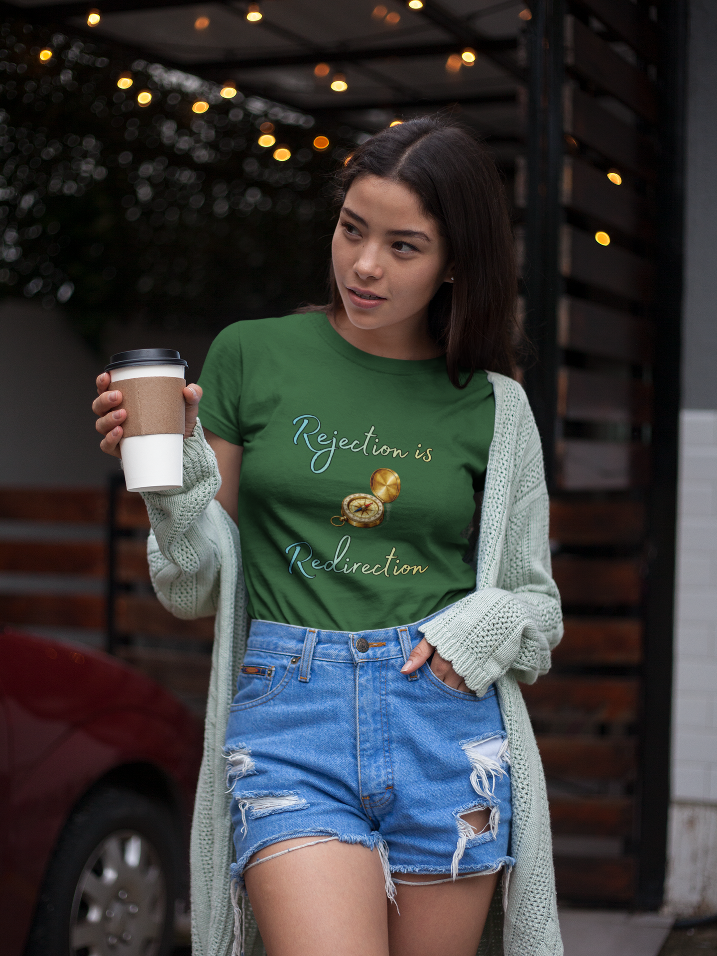 Rejection Is Redirection T-Shirt – Motivational Compass Quote Tee in evergreen green styled casually with coffee and cardigan, featuring the redirection shirt message and compass illustration