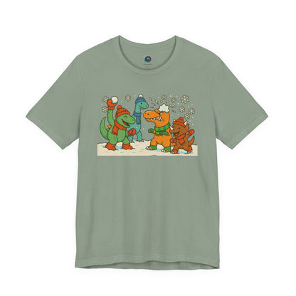 the Dinosaur Snowball Fight T-Shirt – Funny Winter Dino Graphic Tee in Sage, combining a calm winter tone with the cartoon dinosaur snow battle.