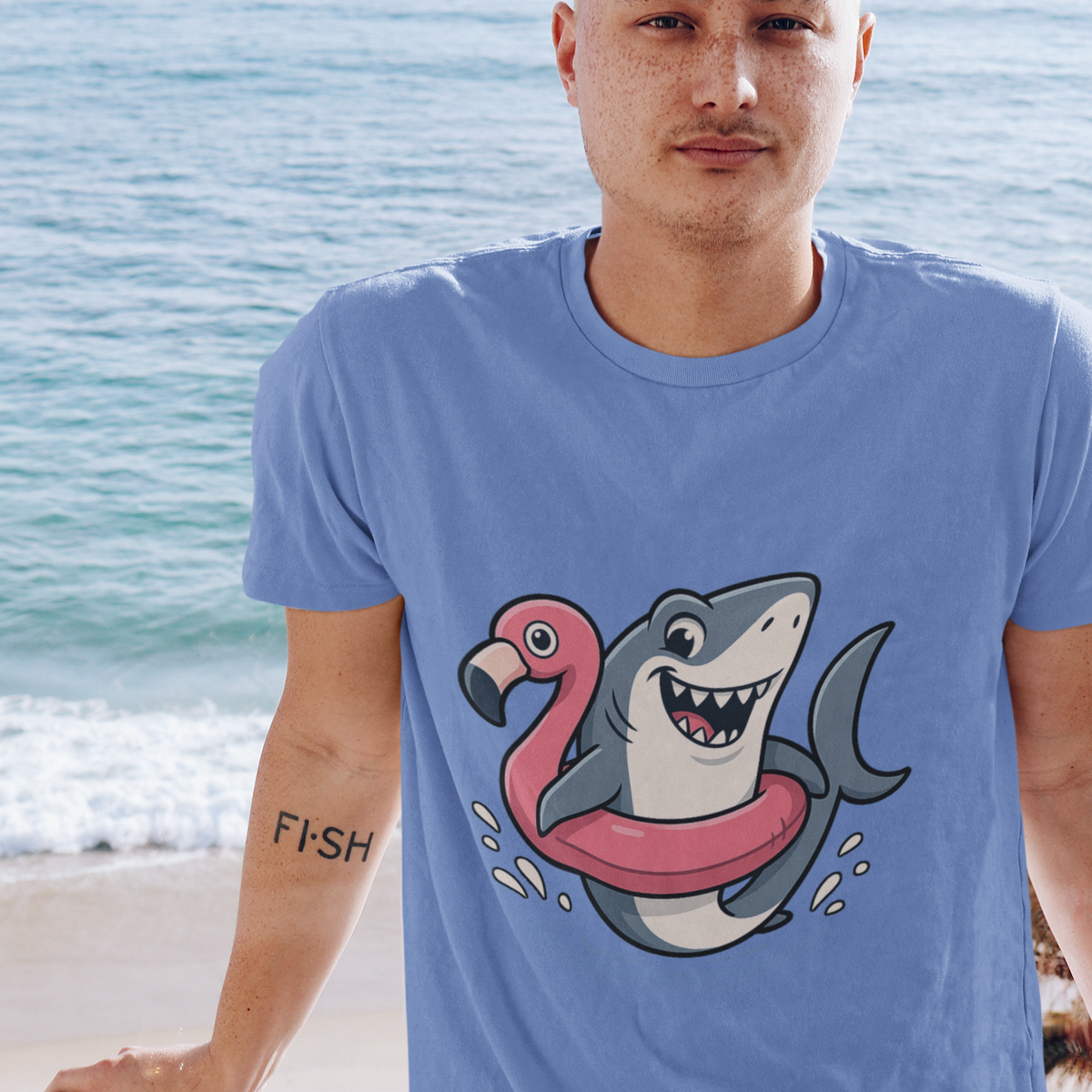 Man at the beach wearing the Shark Flamingo Floatie T-Shirt – Funny Beach & Pool Day Tee, with ocean in background