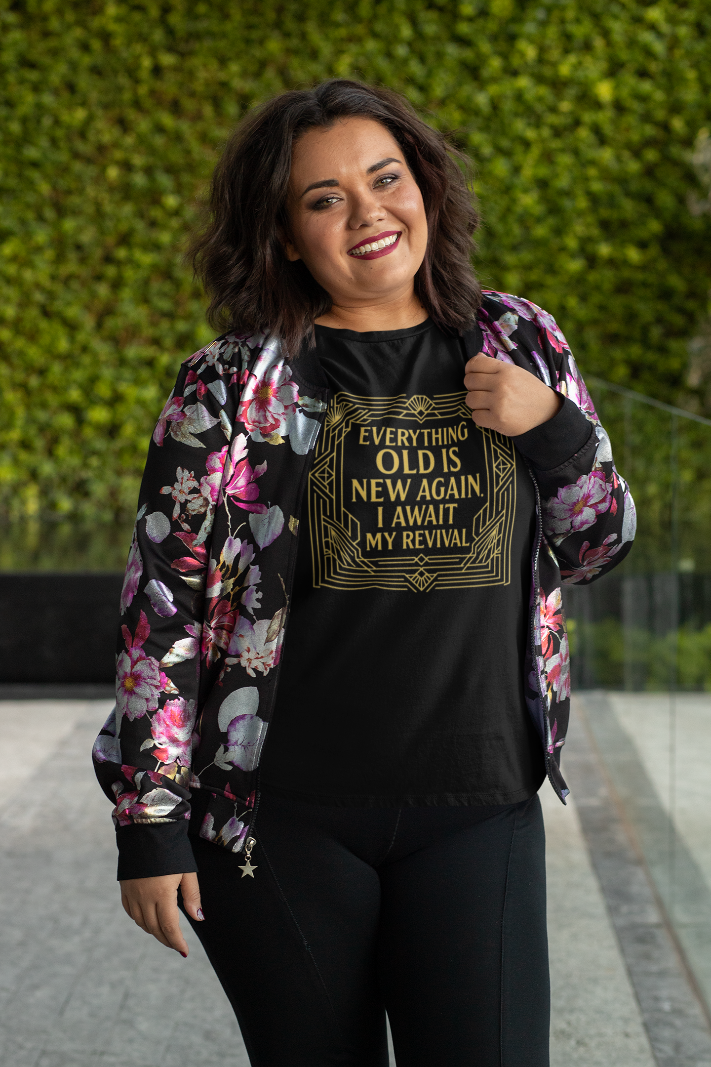 Woman smiling brightly in floral jacket and black shirt with gold Art Nouveau border that reads Everything Old Is New Again – I Await My Reviva