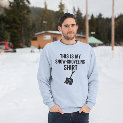 This Is My Snow-Shoveling Shirt – Funny Winter Chore Sweatshirt worn by a man standing outdoors in a snowy winter setting with cabins in the background, featuring the snow shovel graphic and bold winter humor