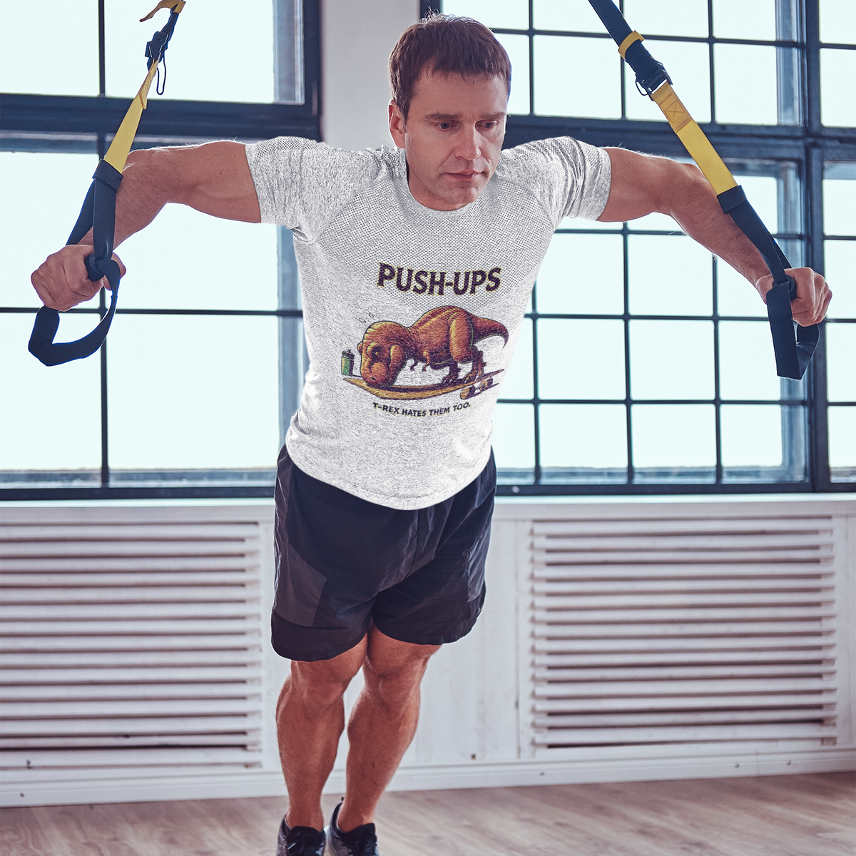 T-Rex Push-Up T-Shirt – Funny Dinosaur Workout Graphic Tee featuring a comical t rex hates push ups design, shown during a TRX workout for fitness lovers.