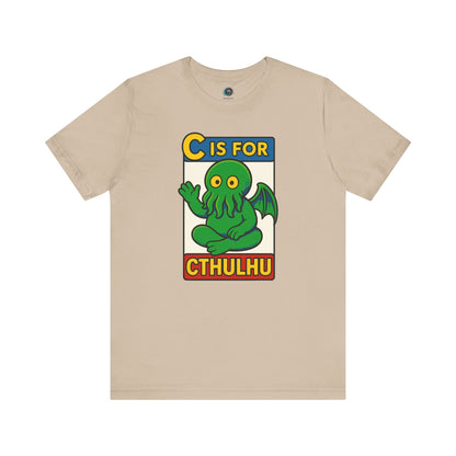 C is for Cthulhu T-Shirt – Lovecraftian Funny Cartoon Tee in tan, flat lay design with cute Cthulhu cartoon from monster alphabet series.