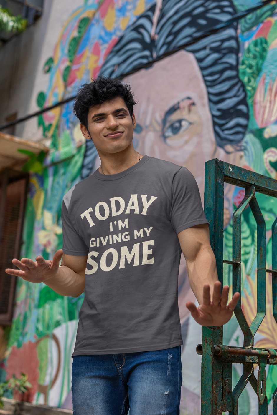 Today I’m Giving My Some T-Shirt – Funny Low Energy Graphic Tee shown in Asphalt as a man smirks and gestures casually in front of a colorful urban mural
