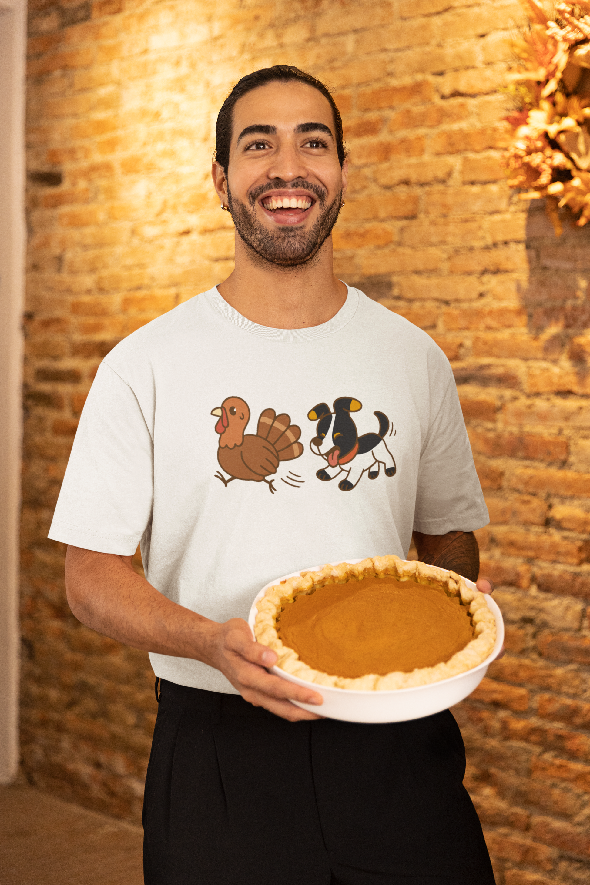 Dog Chasing Turkey T-Shirt – Funny Thanksgiving Dog Tee in white with cartoon dog and turkey, worn by smiling man
