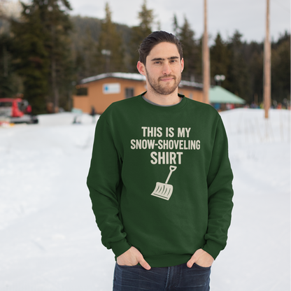 This Is My Snow-Shoveling Shirt – Funny Winter Chore Sweatshirt  in forest green worn in a snowy outdoor scene, featuring the snow shovel graphic and winter-ready style