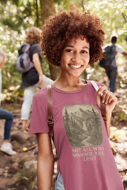 Smiling woman on a forest hike wearing heather raspberry “Not All Who Wander Are Lost T-Shirt – Tolkien Travel Tee for Nature Lovers” with nature scene design featuring trees and mountains
