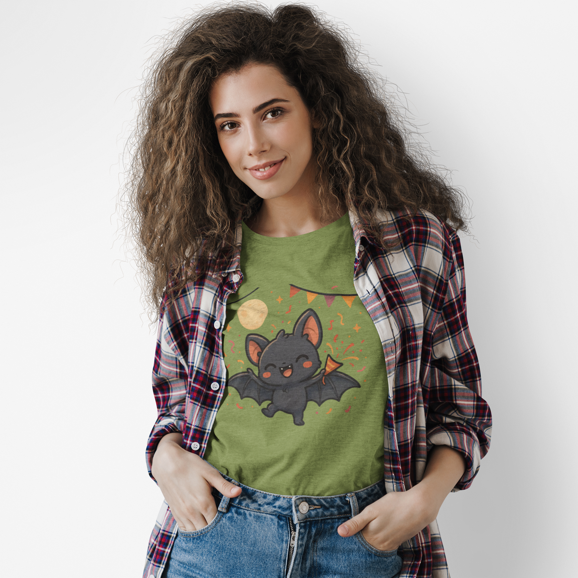 Woman standing indoors wearing the Chibi Bat T-Shirt – Cute Bat Chibi Halloween Shirt for All Ages in military green, styled with a plaid shirt and showing a playful chibi bat surrounded by party decorations.