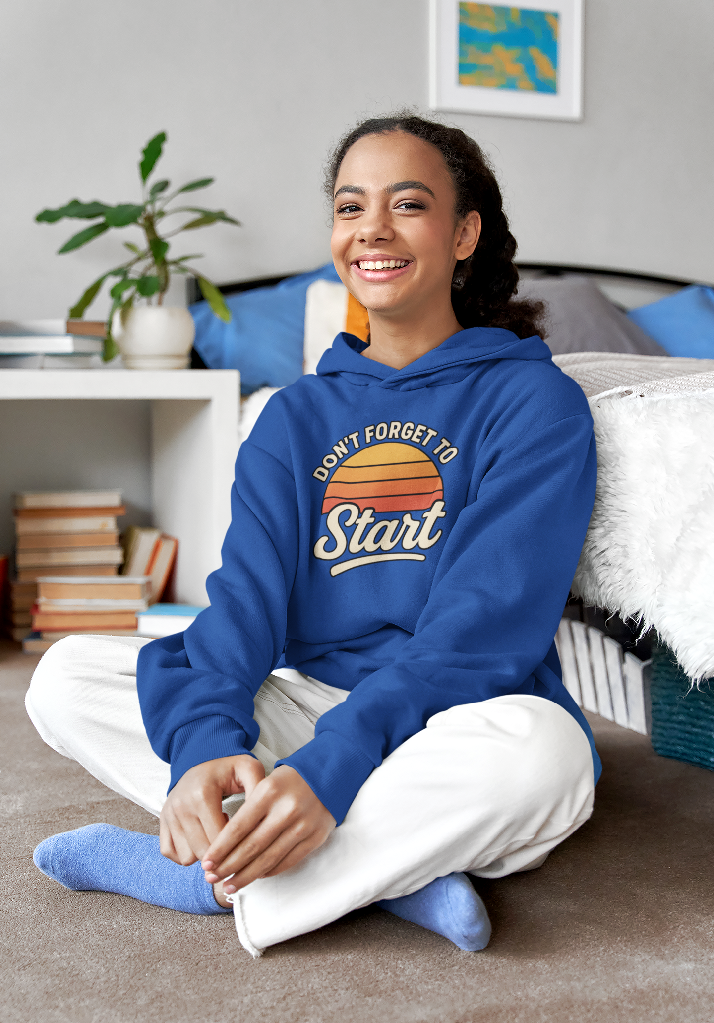 Don’t Forget to Start Hoodie – Retro Sunrise Motivational Sweatshirt in blue, worn while seated indoors, featuring the retro sunset stripes and relaxed fit.