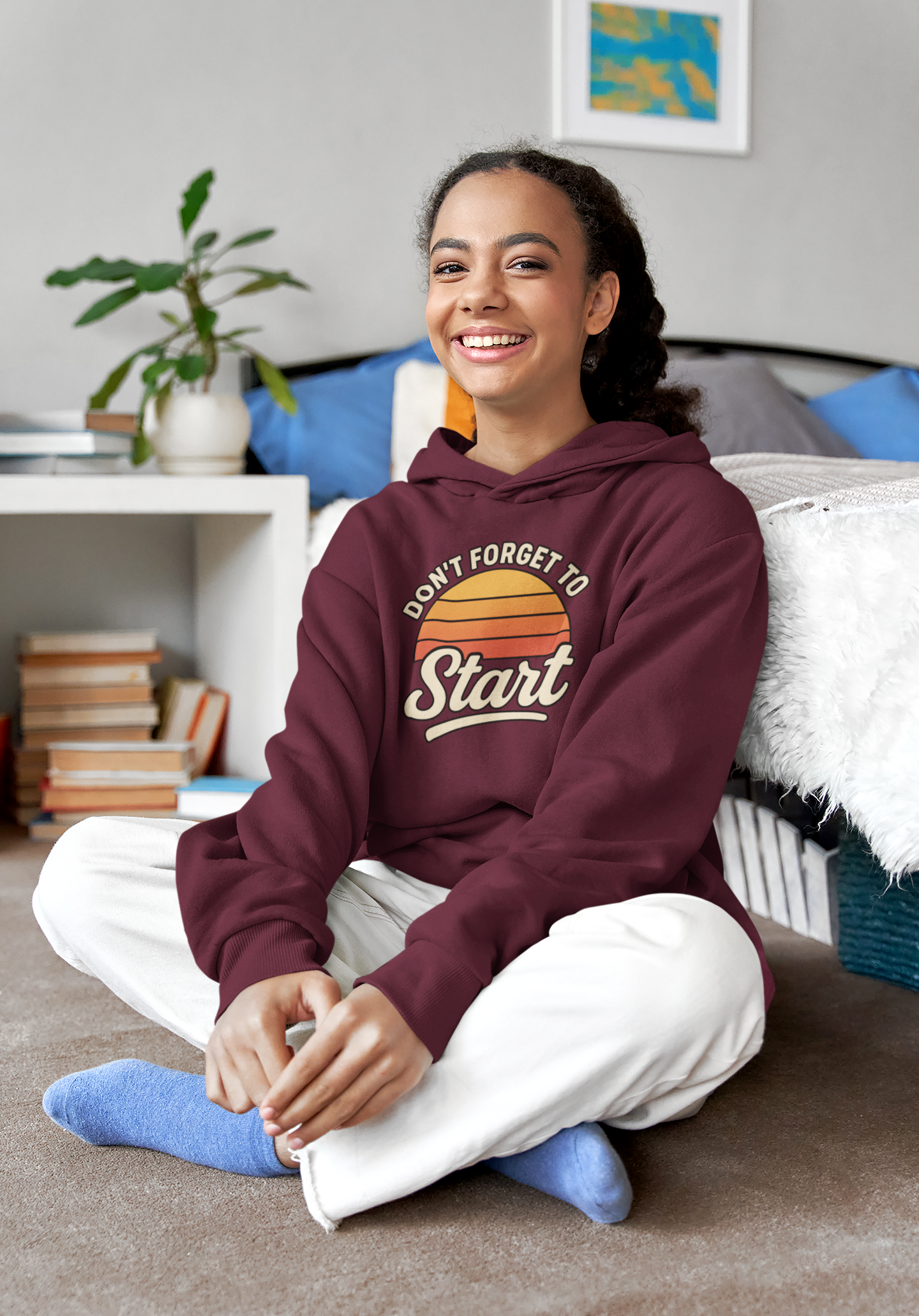 Don’t Forget to Start Hoodie – Retro Sunrise Motivational Sweatshirt in burgundy, shown in a cozy living room environment highlighting the soft fabric and inspirational design.