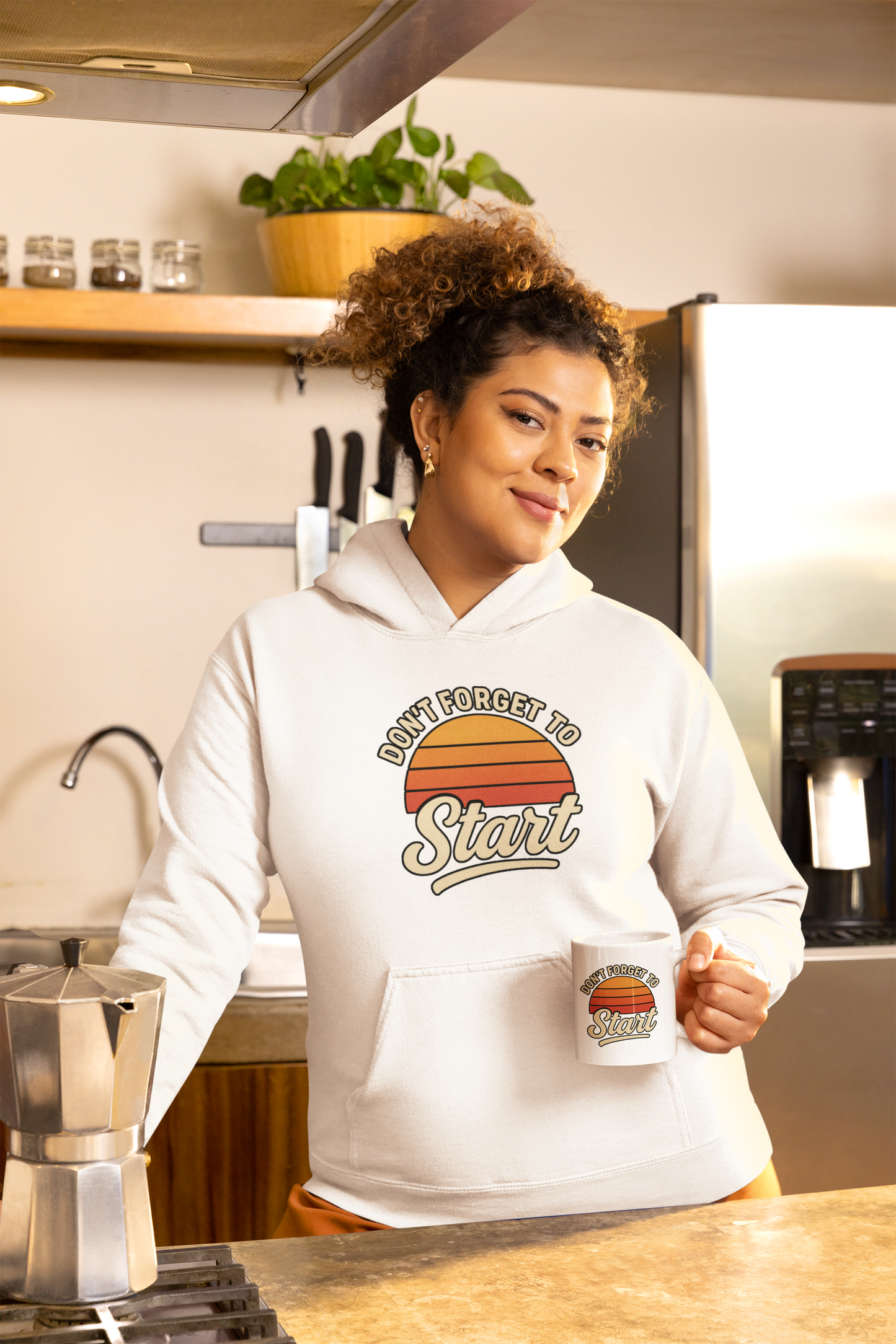 Don’t Forget to Start Hoodie – Retro Sunrise Motivational Sweatshirt styled indoors with a coffee mug, emphasizing the warm vintage colors and uplifting message.