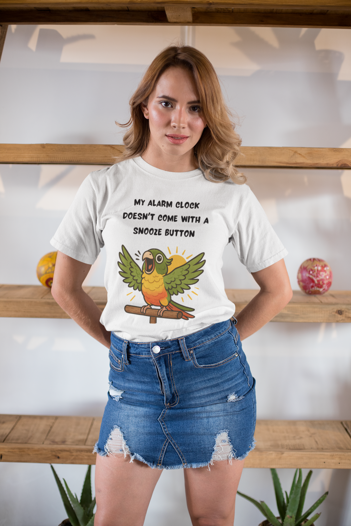 A woman modeling the Parrot Alarm Clock T-Shirt – Funny Parrot Wake-Up Call Tee in white, highlighting the bright parrot character and energetic morning message in an indoor studio-style space.
