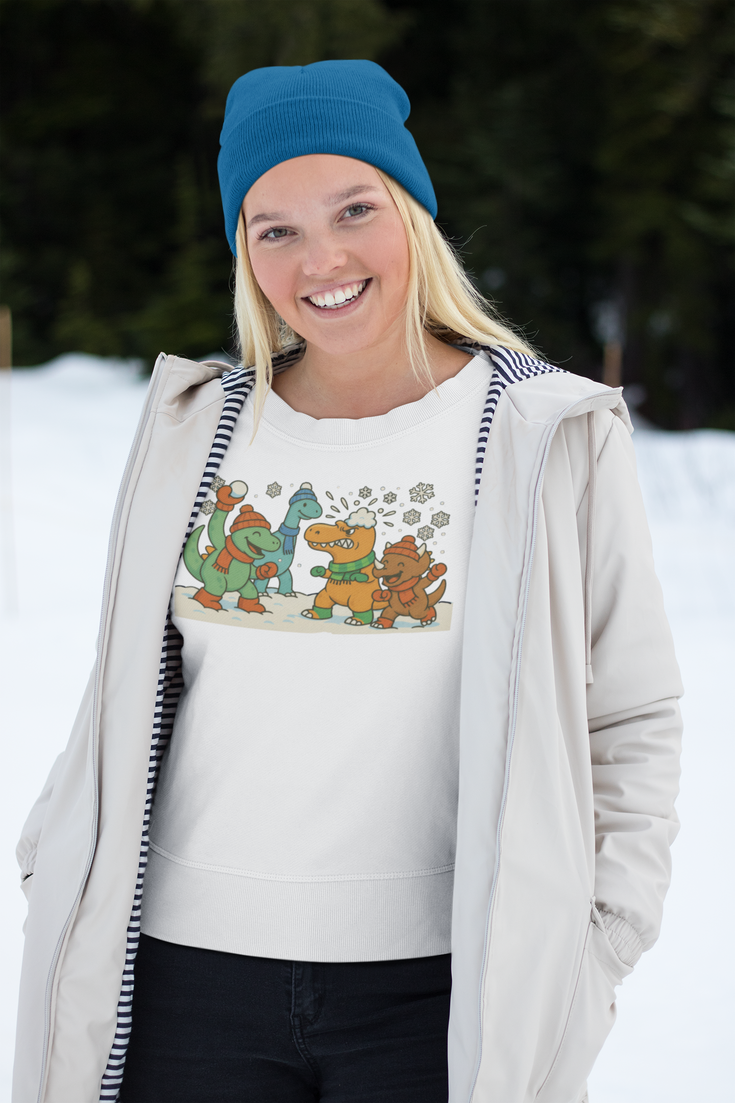 a woman wearing the Dinosaur Snowball Fight T-Shirt – Funny Winter Dino Graphic Tee in white, highlighting the playful dinosaur snow battle illustration against a winter backdrop.