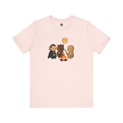 Halloween Monsters Campfire T-Shirt in soft pink by WhimSpin, featuring a cute monster campfire scene with marshmallows and a glowing moon.